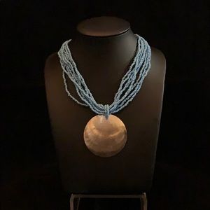 Blue beaded necklace with large shell pendant.